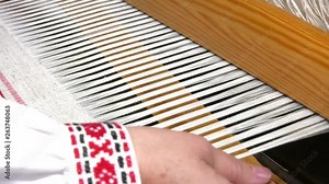A traditional hand-weaving loom being used to make cloth. Hands of a man who weaves on a loom