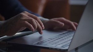 Married adult hand scrolling on laptop touchpad.