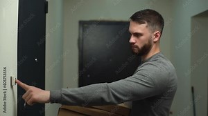 Side view of frustrated delivery man delivering boxes with hot pizza to client on doorstep at apartment. Courier does not open door, rings doorbell several times. Shooting in slow motion.