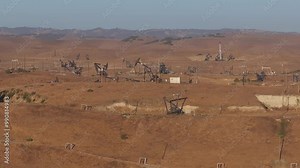 Aerial view of the oil rigs and wells in the Midway-Sunset shale oil fields, the largest in California. A pumpjack operates at an oil field. Oil pump rig energy industrial machine for petroleum.
