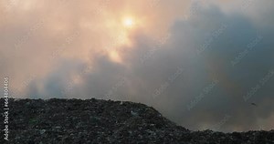 A fire in a landfill, everything is filled with thick toxic smoke. Ecological disaster, birds fly around burning garbage. Problem with recycling garbage and plastic waste. Fire on a garbage heap.