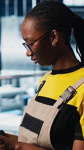 Vertical Smart factory engineer implements automated workflows using artificial intelligence tech, computerizing manual operations. Woman integrates sensors into production using AI technology, camera A