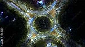 Top view of city street traffic on roundabout intersection at night with fast moving cars. Timelapse of illuminated urban circular transportation crossroads