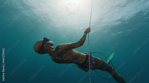 Woman freediver makes bubble ring underwater. Female freediver has fun and creates bubble ring being on the depth