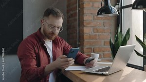 Serious man typing credit card number on his mobile phone, buying items from online application, transferring money while sitting at the cafe. Credit card and a smartphone in male hands