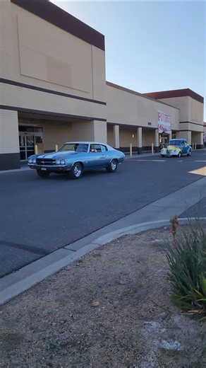 Chevrolet chevelle ss in light blue leading custom ford coupe hotrod at classic car meet
