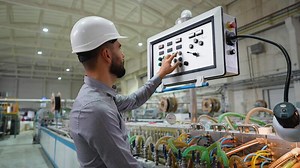 Industrial engineer working at programmable CNC machine in window factory