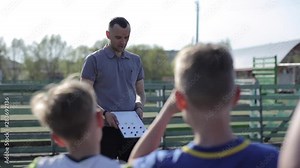 Young Football coach trainer coaching kids using tactic strategy magnetic whiteboard. Soccer trainer explaining match tactics to children soccer team.