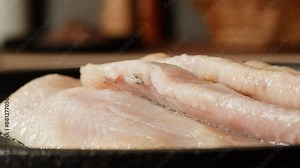 Raw herring fish slices a black plate close-up macro. Marinated herring fillet in oil and spices for appetizer. Raw seafood products