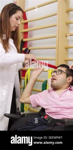 Young man with a disability in a wheelchair performing physical therapy exercises. A female therapist is assisting him with a resistance band Stock Video Footage - Alamy