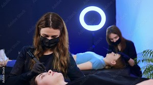 Masters of brow make up working in the salon. Beauty specialists use tools to perform procedure.