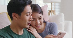 Asia people young family man woman smile happy fun laugh look at phone sit at home pay for hotel booking, search choose, buy ticket on social media app for budget travel abroad trip getaway plan tour.