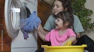 Mother and child wash clothes. Happy mom with her daughter at the washing machine.