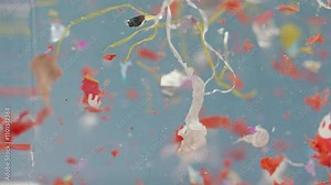 Microplastic pieces drift in water in slow motion, representing lab analysis on environmental pollution and waste issues.