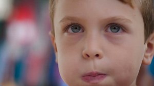 Close up of a young boy puffing up his cheeks like he is blowing and moving his tongue around inside his mouth - slow motion