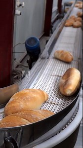 Bread Factory Interior with Hot Baked Bread Moving Along Bread Packaging Line. Freshly Baked Bread Ready for Delivery to the Market. Industrial Bakery Equipment. Bread Factory Production Line.