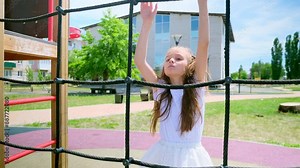 Happy Little girl climbing rope net at outdoor playground in the park on summer vacation. Child kid enjoy outdoor activity playing and learning at school playground