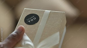 hand putting a thank you sticker on a gift box
