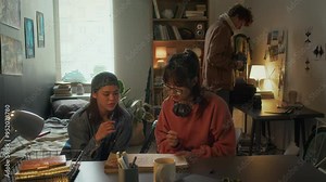 Medium shot of group of three diverse cinematography college students working on their movie, preparing graduate project gathered together at home, copy space