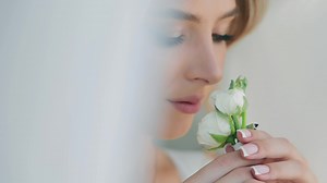 Portrait of a beautiful bride smelling small white roses and looking into the distance. Beautiful blonde on her wedding day. Up close