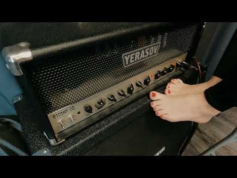 With bare feet girl tunes a guitar amplifier