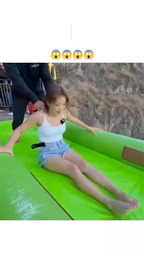 education.decodee on Instagram: "- The post features a 10-second video of a woman accelerating down a steep green-to-blue inflatable waterslide on a mountainside cliff, landing in a pool near a river below, accompanied by excited narration like "Double bounce dead center." - With 2.2 million views and 140+ replies in under 12 hours, it sparks intense debate on realism, as users cite unnatural slide stability and motion blur as signs of AI generation amid 2025's deepfake trends. - While real clif