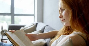 Woman reading a book in living room