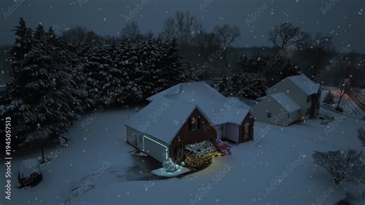 Soft snowfall in Americans neighborhood with lighting houses and decorated front yard during. Christmas season. Cozy and charming suburb residential area in America. Descend drone shot.