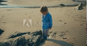 Little toddler in socks getting feet wet on beach