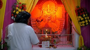 Indian priest worshipping in the temple/mandir of Goddess Durga(Sherawali maa). Still shot of a Hindu pujari in traditional clothing doing Aarti of Sherawali Mata idol - spiritual traditions follow...