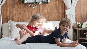 Cute sweet toddler children, tickling feet on the bed, laughing and smiling
