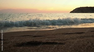 Waves gently lap at shore during stunning sunset over ocean. Golden sunlight reflects off waves as they roll onto shore, creating tranquil atmosphere at sunset by sea. Montenegro summer Canj