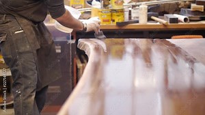 An artisan furniture maker is carefully varnishing a hand crafted natural wood tabletop in his wood shop. Stock Video