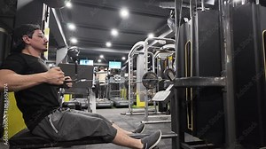 -Young, Strong, Handsome Bodybuilder Training Lower Back with Wide-Grip Rod on Seated Row Cable, Performing Intense Endurance Workout in Gym,Side View Stock Video