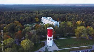 Kemeri Water Tower With Latvian Flag in the Kemeri Resort Park in Jurmala, Latvia. Beautiful White Neoclassicism Architecture House in Background. Aerial View From Above. Colorfull Autumn Evening