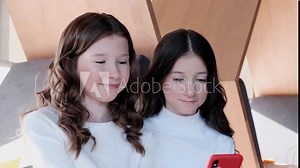 Two cheerful girlfriends playing a game using a smartphone.