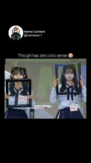 Meme Content on Instagram: "This video captures a humorous and chaotic moment from what appears to be a Japanese variety show. Two young women in school uniform-style outfits are standing behind a table, each holding a large, empty picture frame. The woman on the right begins a comedic routine where she physically interacts with her frame as if it were a solid object or a magical portal. She starts by "dipping" herself through the frame, leaning her torso through the center and popping back up, 