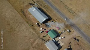 Aerial circle around rural farm barn fire smoke 4K. Farming and ranch facility with storage barns and buildings. Fire department respond to spontaneous fire inside hay bales and feed.