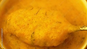 Homemade tasty thick pumpkin soup puree stirred with a spoon close up. Vegan, vegetarian food.