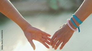 Two woman tenderly hold hands. Romantic couple