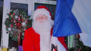 Santa Claus lovingly wishes all the French people happiness, waving the flag and singing the French anthem on a Festive Christmas background with a Christmas tree and garlands Stock Video