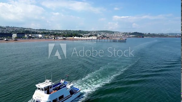 Paignton, Torbay, South Devon, England: DRONE VIEWS: Paignton Pier and seafront as a passenger boat heads towards Paignton harbour. Torbay is a popular UK holiday destination with many attractions.