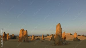 Limestone pillars in the scenic sandy Pinnacles Desert of the Nambung National Park in Western Australia, with blue sky and horizon as background.