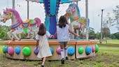 Rear view of two Asian girls having fun walking in an amusement park,...