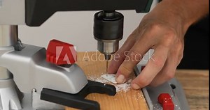 DIY man drilling holes in small particle, using stable hand drill, close up