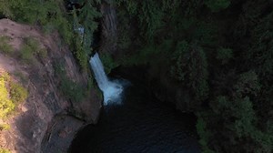 River Cascades Into Deep Blue Pool in Early Morning From High Above