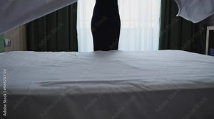 Unrecognizable woman making bed in hotel room. Maid cleaning room. Hotel room service.