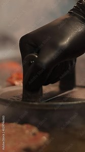 Closeup vertical footage of chef's hand using a burger press to press the meatball down on the grill