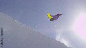 SLOW MOTION: Young pro snowboarder riding the half pipe in big mountain snow park, jumping out of the halfpipe wall and over the sun, performing tricks and rotations with grabs in sunny winter