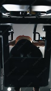 Low angle view Fitness woman working out in gym doing exercise for biceps. Woman on rowing machine for health, wellness, body. Multi station at gym for arm, shoulders muscles. Vertical shot